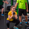 Trening z trenerem-personalnym a także trening z trenerem personalnym w parach w Gdańsku. Dziewczyna w prawidłowej postawie trzyma hantel.