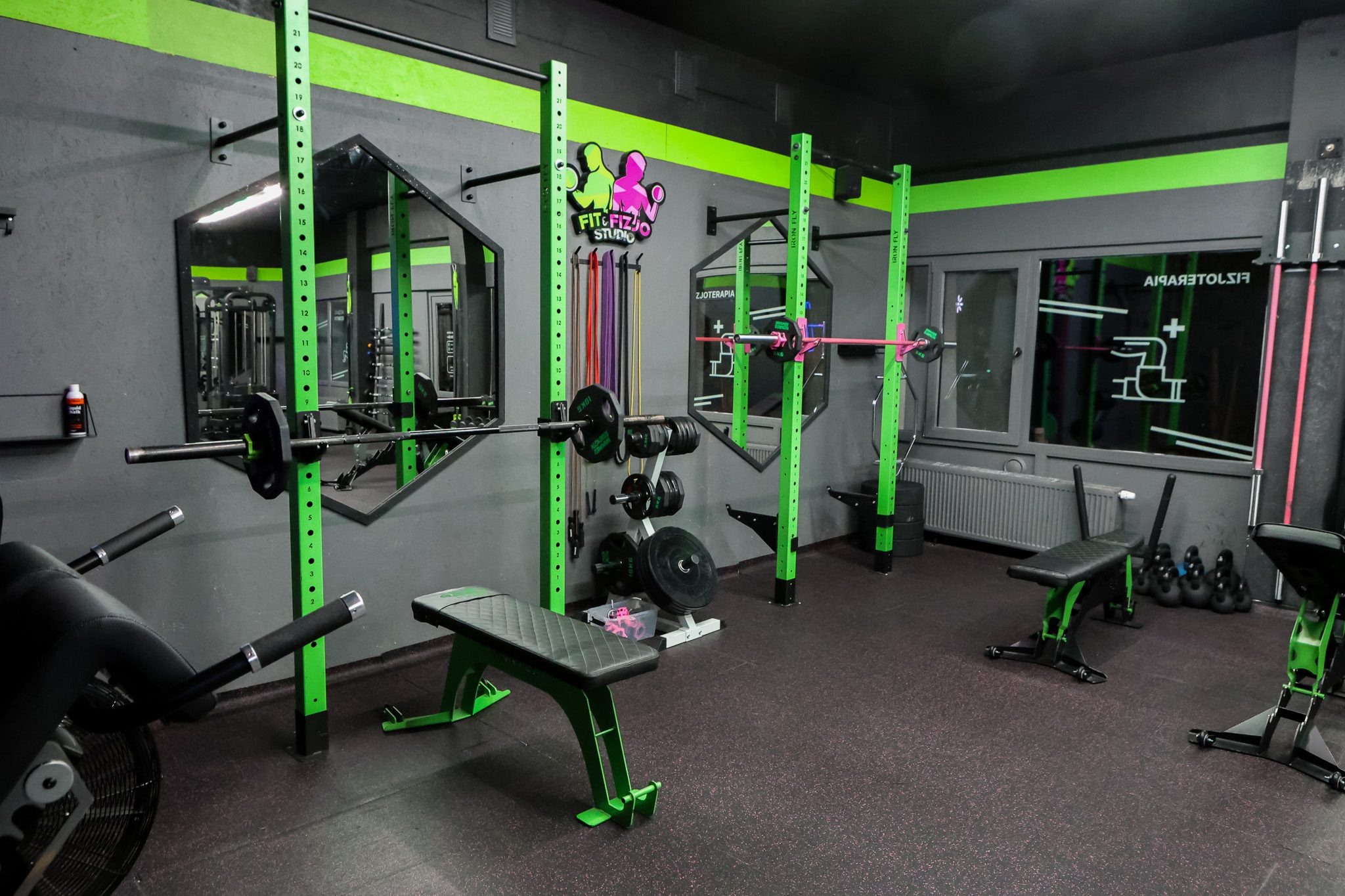 Strefa wolnych ciężarów z klatką treningową i ławkami – Fit&Fizjo Studio